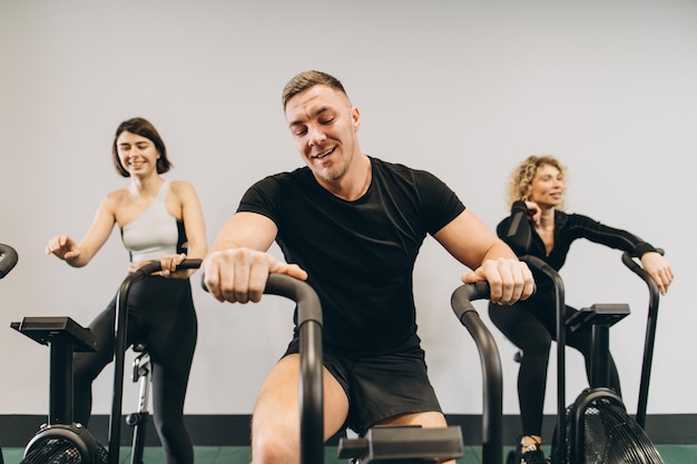 Giovane uomo e donna che usano la bici ad aria per l'allenamento cardio presso la palestra di allenamento incrociato