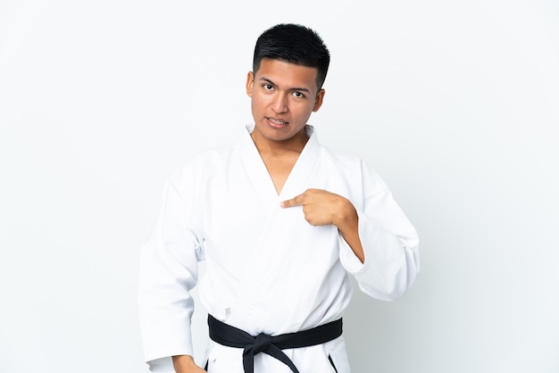 Giovane uomo ecuadoriano che fa karate isolato su priorità bassa bianca con l'espressione facciale di sorpresa