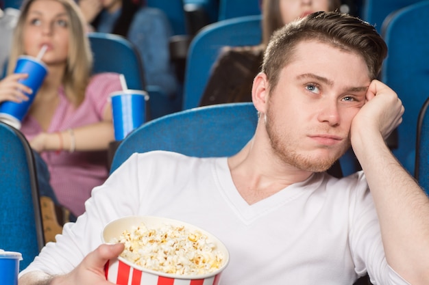 giovane uomo estremamente annoiato guardando un film al cinema