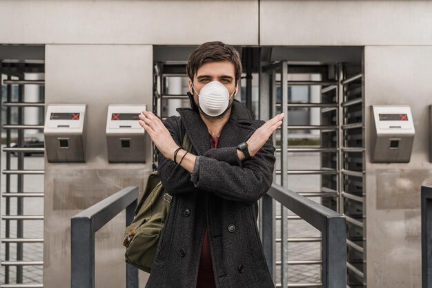 Giovane uomo europeo in maschera protettiva vicino al cancello Fermare l'epidemia o il gesto di inquinamento