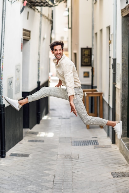 Giovane uomo felice che salta in strada.