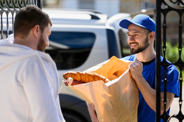 Giovane uomo felice di consegnare la spesa al cliente