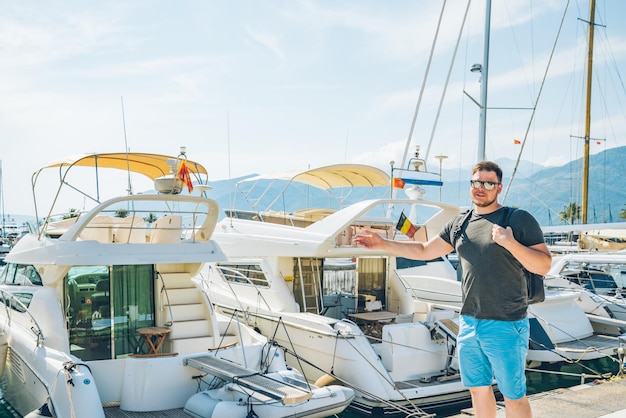 Giovane uomo forte che cammina per la baia della città con il concetto di viaggio estivo di yacht