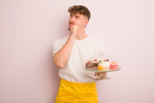 Giovane uomo freddo pensando che si sente dubbioso e confuso concetto di torte fatte in casa