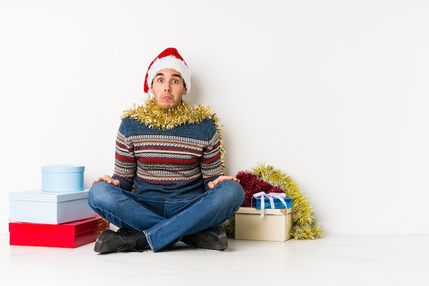 Giovane uomo il giorno di Natale con le dita sulle labbra mantenendo un segreto.