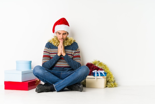 Giovane uomo il giorno di Natale piegando le labbra e tenendo le palme per inviare bacio dell'aria.