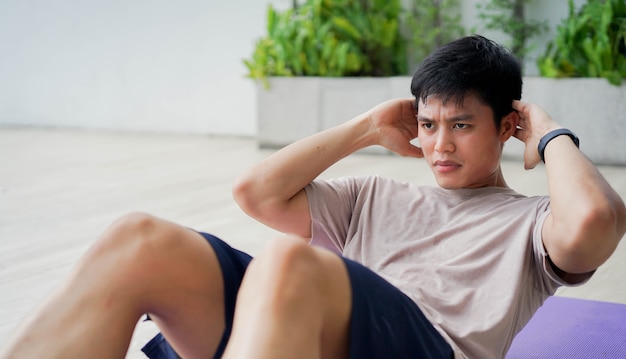 giovane uomo in allenamento modello sit-up sulla stuoia di esercizio in palestra di casa al mattino