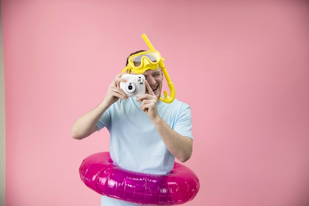 Giovane uomo in anello di nuoto gonfiabile con maschera per lo snorkeling e tubo che fa foto