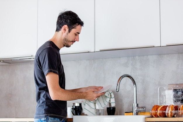 Giovane uomo in camicia nera che cucina in cucina a casa. visione schietta