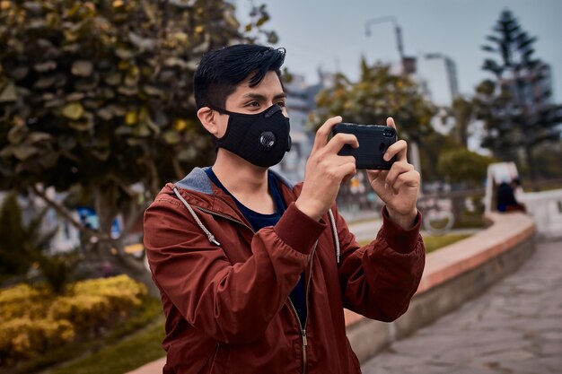 Giovane uomo in maschera a scattare foto