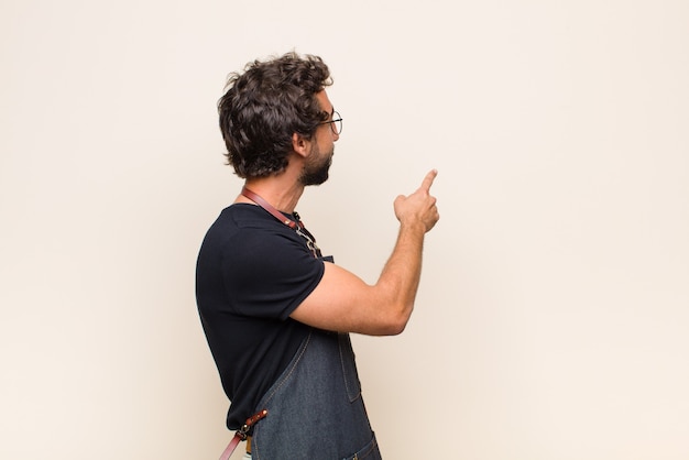 Giovane uomo in piedi e indicando un oggetto sullo spazio della copia, vista posteriore