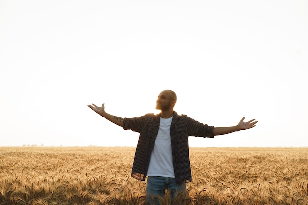 Giovane uomo in piedi nel campo di grano al tramonto