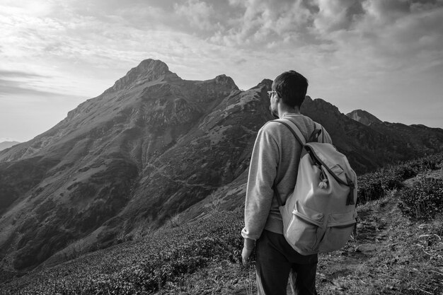 Giovane uomo in piedi sulla cima della scogliera in montagna estiva al tramonto e godersi la vista della natura L'idea e il concetto di fotografia di escursionismo e di viaggio Località sciistica in Russia Rosa Khutor Rosa Peak