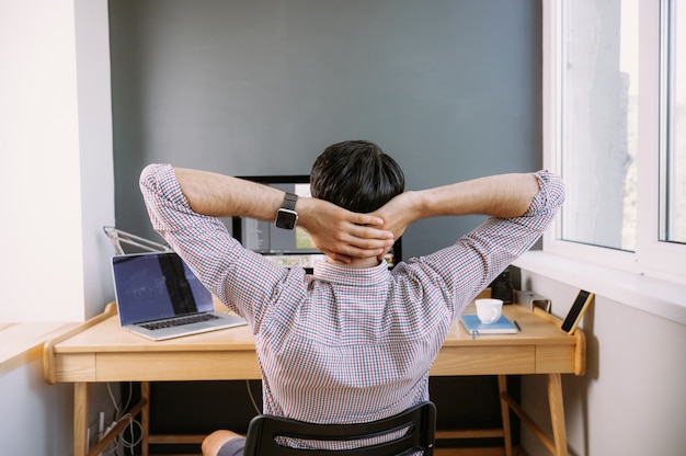 Giovane uomo in una camicia che lavora su un computer a casa