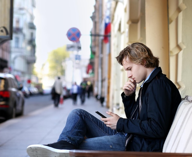 giovane uomo in una strada della città che usa uno smartphone