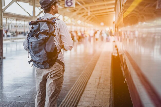 Giovane uomo in viaggio zaino in spalla nel concetto di stazione ferroviaria.travel.