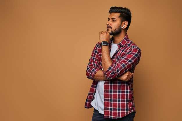 Giovane uomo indiano bello in chiusura casual con le braccia incrociate sul muro pastello