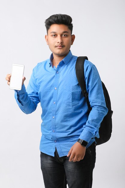 Giovane uomo indiano che mostra lo schermo dello smartphone su sfondo bianco.