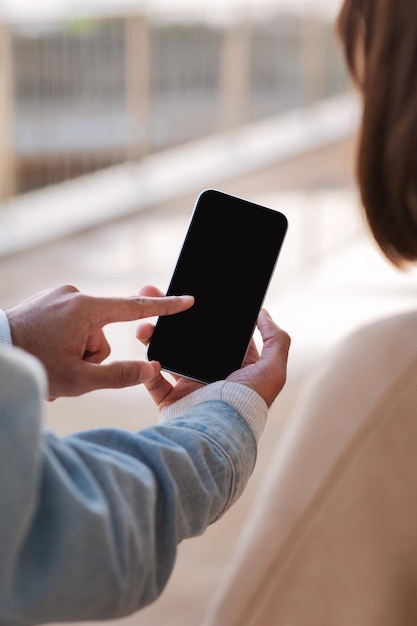 Giovane uomo indiano che mostra smartphone con schermo vuoto al turista femminile caucasico