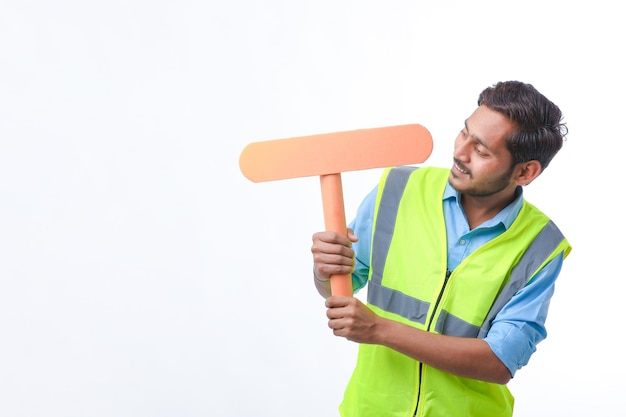 Giovane uomo indiano che tiene un cartello vuoto su sfondo bianco. concetto di lavoro di costruzione