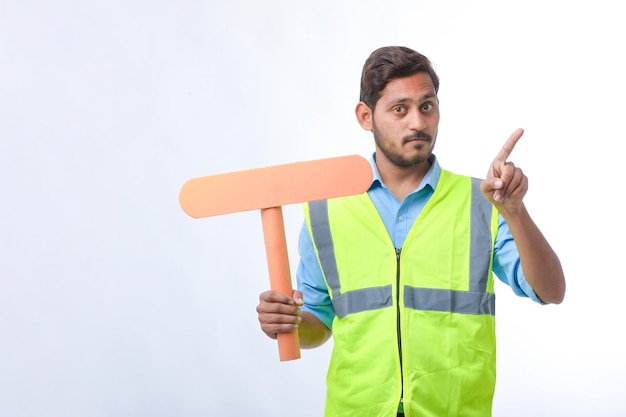 Giovane uomo indiano che tiene un cartello vuoto su sfondo bianco. concetto di lavoro di costruzione