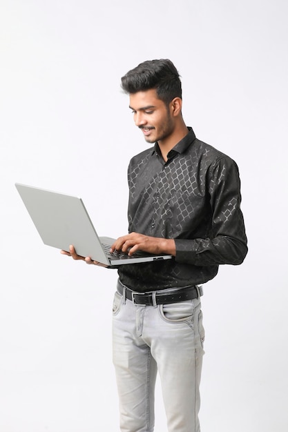 Giovane uomo indiano che utilizza laptop su sfondo bianco.