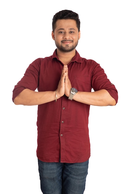 Giovane uomo indiano con un'espressione di benvenuto o invitando o salutando Namaste su uno sfondo bianco
