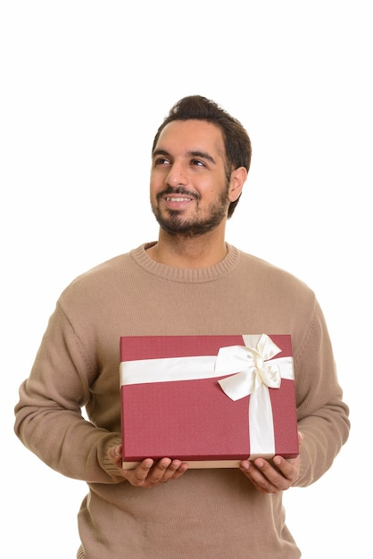 Giovane uomo indiano felice che tiene confezione regalo mentre si pensa