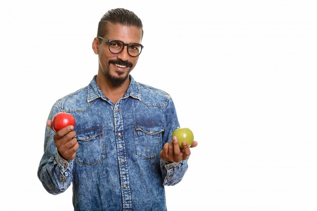 Giovane uomo indiano felice che tiene mela rossa e verde isolata