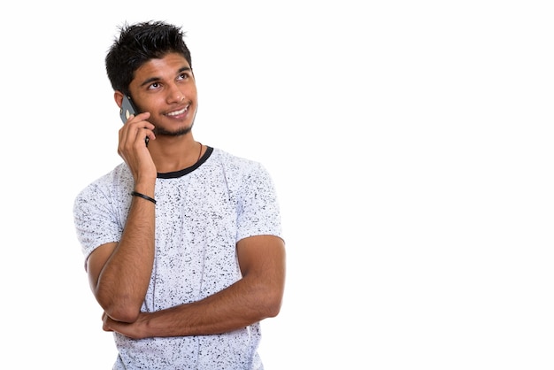 giovane uomo indiano felice sorridente e parlando al telefono cellulare