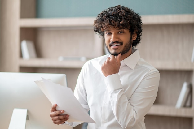 Giovane uomo indiano in una camicia bianca in ufficio