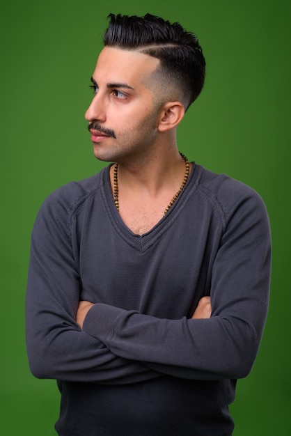 Giovane uomo iraniano bello con i baffi sul verde