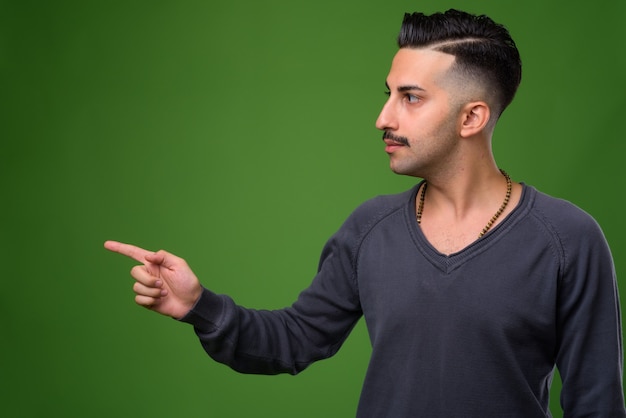 Giovane uomo iraniano bello con i baffi sul verde