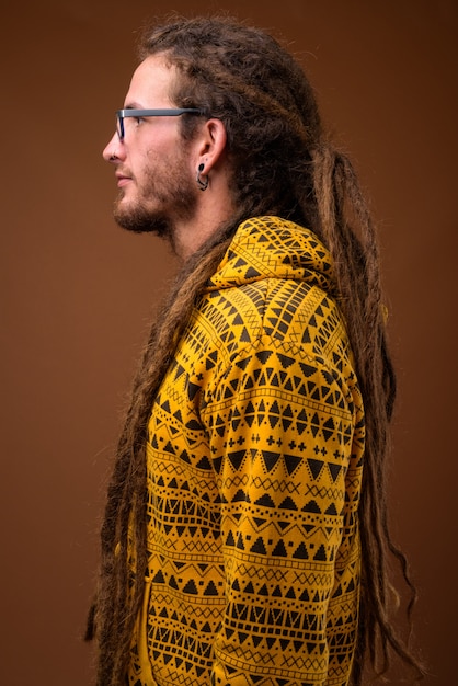 Giovane uomo ispanico bello con i dreadlocks contro backgr marrone