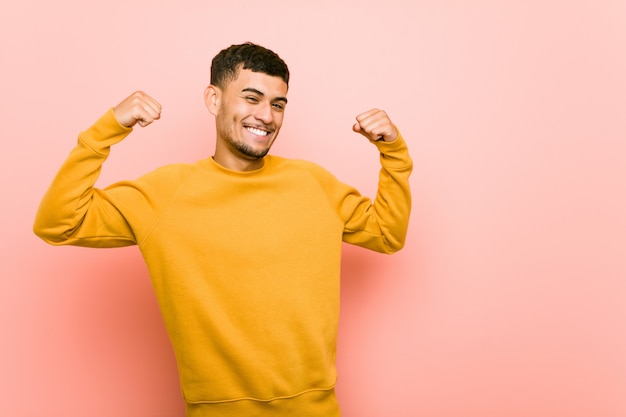 Giovane uomo ispanico che mostra gesto di forza con le braccia, simbolo del potere femminile