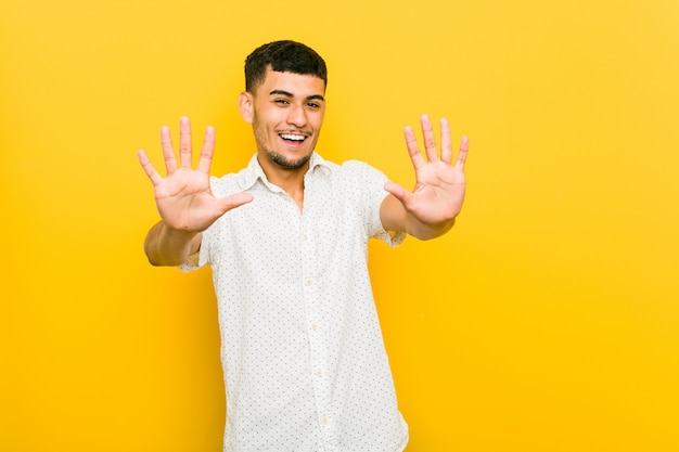 Giovane uomo ispanico che mostra numero dieci con le mani.