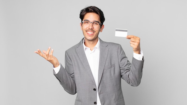 Giovane uomo ispanico che si sente felice, sorpreso nel realizzare una soluzione o un'idea e in possesso di una carta di credito