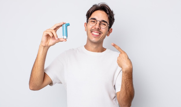 Giovane uomo ispanico che sorride con sicurezza indicando il proprio ampio sorriso. concetto di asma