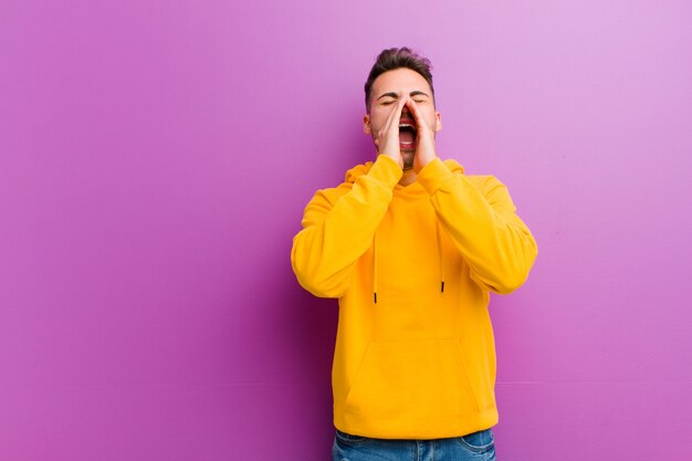 Giovane uomo ispanico con look casual contro il muro viola