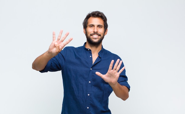 Giovane uomo latino bello sorridente e guardando amichevole, mostrando il numero nove o nono con la mano in avanti, conto alla rovescia