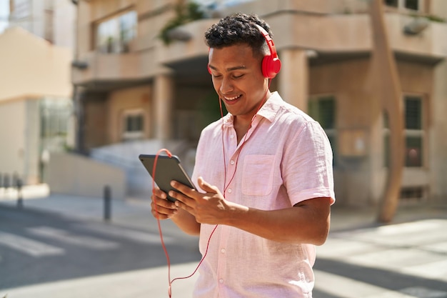 Giovane uomo latino che guarda video sul touchpad in strada