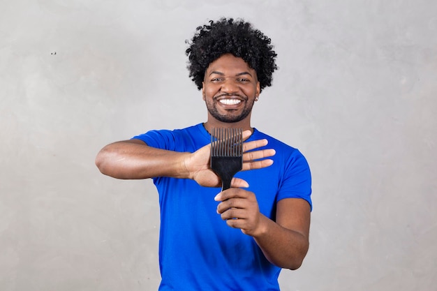 Giovane uomo latino che pettina i capelli Forchetta per pettinare i capelli arricciati Sfondo grigio