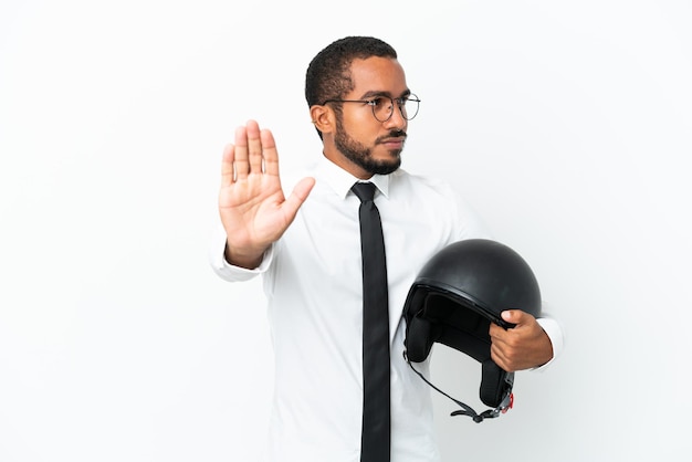 Giovane uomo latino d'affari con un casco da motociclista isolato su sfondo bianco che fa un gesto di arresto e deluso