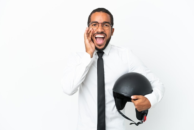 Giovane uomo latino d'affari con un casco da motociclista isolato su sfondo bianco che grida con la bocca spalancata