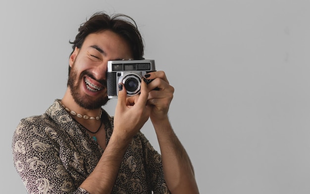 Giovane uomo latino sorridente a scattare foto con chiodi dipinti su sfondo bianco Copia spazio