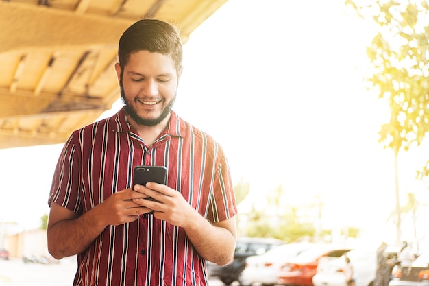 Giovane uomo latinoamericano utilizzando un telefono cellulare