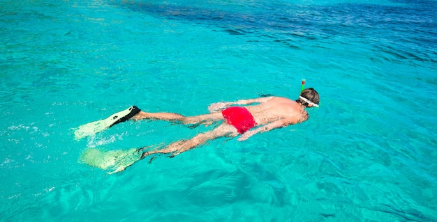 Giovane uomo lo snorkeling in acque turchesi tropicali chiare