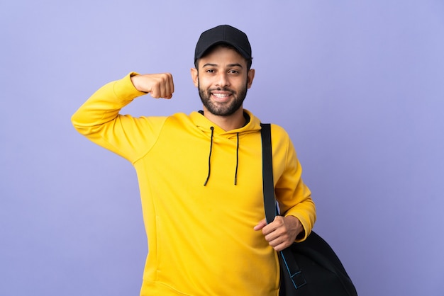 Giovane uomo marocchino di sport con la borsa di sport isolata sulla parete viola che fa forte gesto