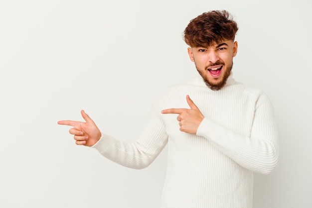 Giovane uomo marocchino isolato su bianco che punta con gli indici a uno spazio di copia, esprimendo eccitazione e desiderio.