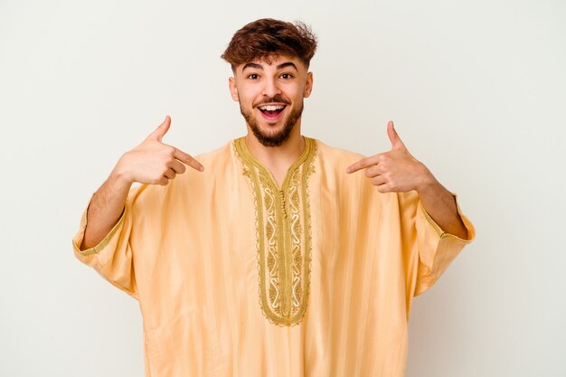 Giovane uomo marocchino isolato sul muro bianco sorpreso indicando con il dito, sorridendo ampiamente.